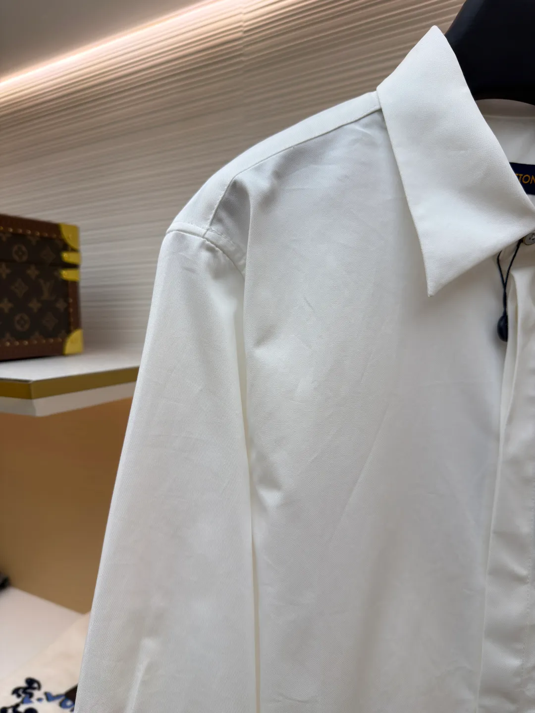 LOUIS VUITTON Embossed Pocket Lapel Shirt ●Original version: Purchased and developed for 3989 ●Item number: 1681491-B05 ●Fabric: Cotton twill woven fabric ●Technology: Concave embossed printing ●Color: white ●Version: Fitted version ●Weight: about 370 grams ●Size: XS-S-M-L ●Description: The twill pattern is obvious on the front of the fabric and blurry on the reverse. Single yarn is used in both warp and weft directions, and the linear density is close. The warp density of the fabric is slightly higher than the weft density, and the hand feel is relatively soft. The fabric has excellent stability, is not easy to deform, and prevents bulging; cotton fiber has good hygroscopicity, which keeps the fabric in a water balance, making people feel comfortable, and adding to the sophistication of the fabric. The concave and convex embossing process is formed by heating and shaping the upper and lower dies. The rollers press the fabric at a certain temperature, and the three-dimensional hierarchical convex surface is produced through mechanical embossing. The fabric produces a concave and convex pattern with a relief-style three-dimensional effect and a special gloss effect. The three-dimensional shape, pattern and text have a strong three-dimensional sense, adding a decorative art effect, clear layers, concentrated three-dimensional image, and accurate perspective angle. The collar can be adjusted with buttons for both formality and comfort; the pleats and tabs at the back are classic shirting techniques, with the pleats providing extra room for movement and the tabs keeping the shirt in shape when hanging. The button front uses custom-fit buttons that are positioned accordingly, and together these details ensure the shirt's functionality and crisp look. The overall wiring is straight and delicate, the fabric is comfortable and soft, and the color is consistent without color difference. It can be matched with the same style to create a fashionable look and control various occasions. Customized accessories, complete with three standards, same style for men and women!